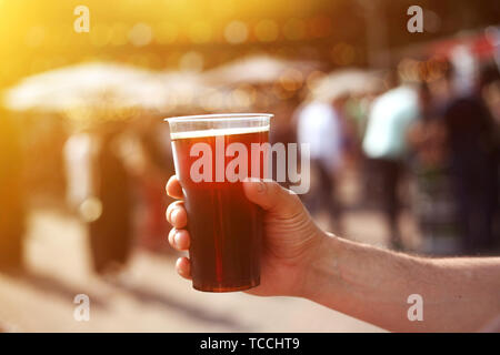 Mann hält ein Glas Bier in der Hand am Bier und Essen Street Festival. Warmes Sonnenlicht. Stockfoto