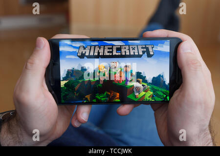 LOS ANGELES, Kalifornien - Juni 3, 2019: Lügen Mann hält ein Smartphone und Spielen minecraft Spiel auf den Bildschirm des Smartphones. Eine erläuternde Editorial Stockfoto