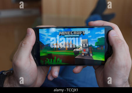 LOS ANGELES, Kalifornien - Juni 3, 2019: Lügen Mann hält ein Smartphone und Spielen minecraft Spiel auf den Bildschirm des Smartphones. Eine erläuternde Editorial Stockfoto