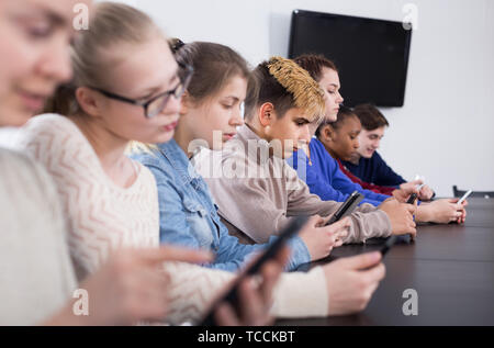 Positive italienische Mitschüler über ihre Smartphones intensiv während der Klassen Stockfoto