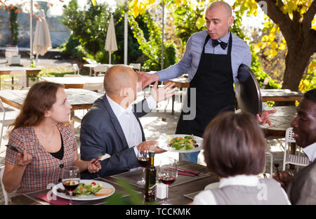 Konflikt zwischen Kellner und Client im open-air Restaurant Stockfoto