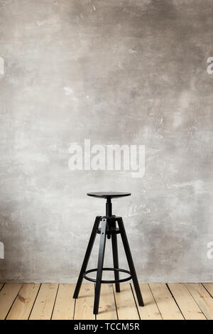 Barhocker auf dem grauen Hintergrund der Wand. Freier Platz für Text. Stockfoto