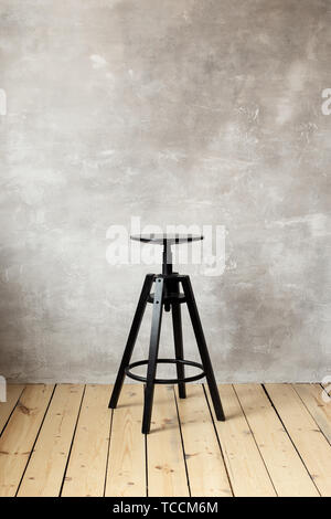 Barhocker auf dem grauen Hintergrund der Wand. Freier Platz für Text. Stockfoto