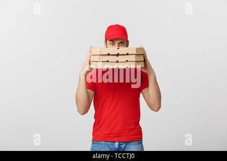 Ein Deliveryman hinter einem großen Stapel von pizzakartons Er trägt, versteckt. Über grauer Hintergrund isoliert. Stockfoto