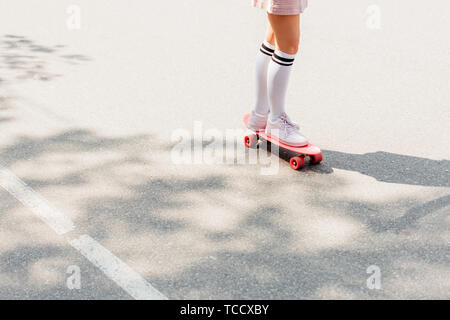 Teilweise mit Blick auf die Mädchen im Knie Socken skateboarding auf der Straße Stockfoto