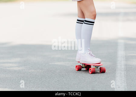 Teilweise mit Blick auf die Mädchen im Knie Socken skateboarding auf der Straße Stockfoto