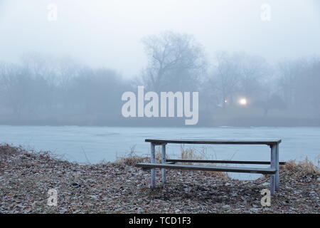 Picknicktisch am Rand eines Flusses an einem düsteren Tag Stockfoto