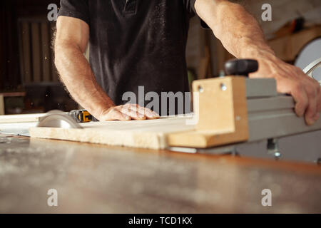 Tischler arbeiten mit einer Bank Säge Bretter, in einer Werkstatt in der Nähe zu niedrigen Winkel Blick auf seine Hände Stockfoto