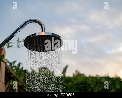 Wasserfall-duschkopf außerhalb in Abend Himmel und Wasser streaming down Stockfoto