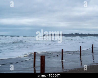 Provisorischen Zaun von Holz- beiträge und Streichern auf einem Sturm Strand mit Wellen kommen an Land. Stockfoto