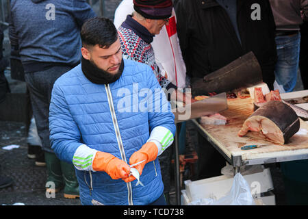 Catania, Italien - Apr 10 2019: fischhändler Herausziehen der Roe und Eingeweide aus einem kleinen Fisch. Ausnehmen ist ein notwendiger Teil der Fischverarbeitung. Traditionelle sizilianische Fischmarkt. Stockfoto