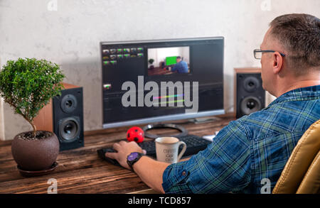 Geschäftsmann oder Fotograf Bearbeiten von Fotos auf einem großen Schreibtisch top Monitor in einem Büro in einem über die Schulter Blick auf seinem Schreibtisch Stockfoto