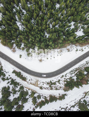 Luftbild des Auto durch den Wald fahren auf verschneiten Straßen. Andorra, Spanien Stockfoto