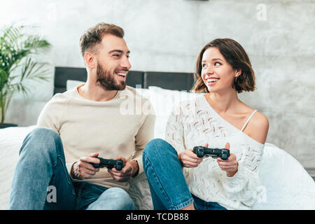 Glückliche Menschen auf fröhliche Frau mit Joystick zu Hause suchen Stockfoto