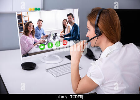Ansicht der Rückseite des Geschäftsfrau das Headset während Videokonferenzen mit Ihren Kollegen Stockfoto