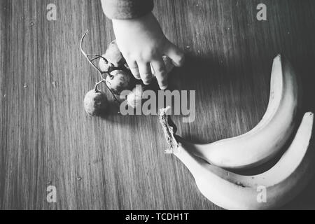 Baby s Hand manipulieren von verschiedenen Früchten auf einem Holztisch Stockfoto