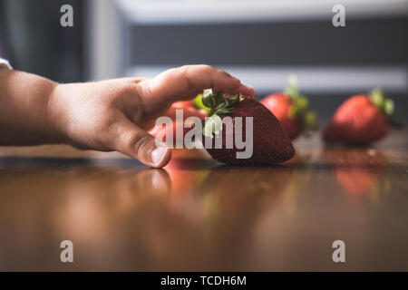 Baby s Hand manipulieren von verschiedenen Früchten auf einem Holztisch Stockfoto