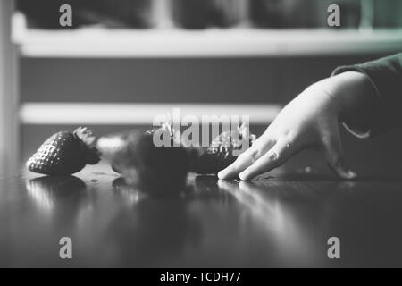 Baby s Hand manipulieren von verschiedenen Früchten auf einem Holztisch Stockfoto