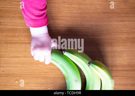 Baby s Hand manipulieren von verschiedenen Früchten auf einem Holztisch Stockfoto