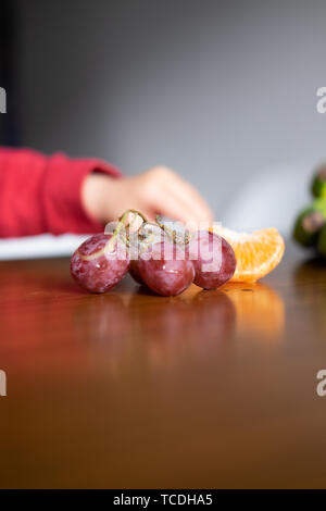 Baby s Hand manipulieren von verschiedenen Früchten auf einem Holztisch Stockfoto