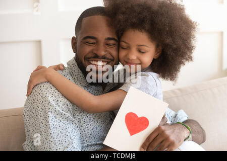 Afrikanischen Vater umarmt Tochter holding Grußkarte am Vatertag Stockfoto