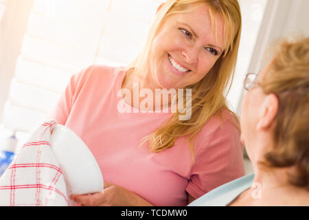 Ältere Erwachsene Frau und Tochter sprechen am Waschbecken in der Küche. Stockfoto