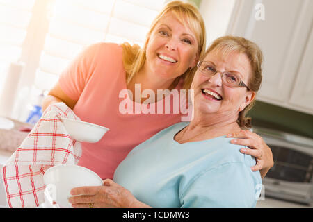 Portrait von lächelnden älteren Erwachsenen Frau und junge Tochter, die an der Spüle in der Küche. Stockfoto