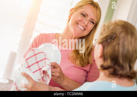 Ältere Erwachsene Frau und Tochter sprechen am Waschbecken in der Küche. Stockfoto