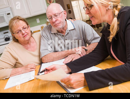 Senior nach Paar über Dokumente in Ihrem Haus mit Agenten zu signieren. Stockfoto
