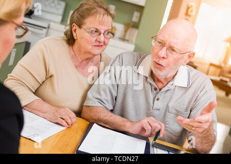 Senior nach Paar über Dokumente in Ihrem Haus mit Agenten zu signieren. Stockfoto