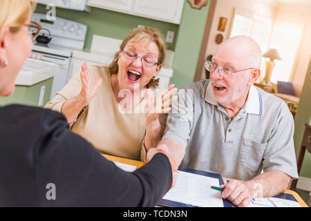Senior nach Paar feiert über Dokumente in Ihrem Haus mit Agenten zu signieren. Stockfoto
