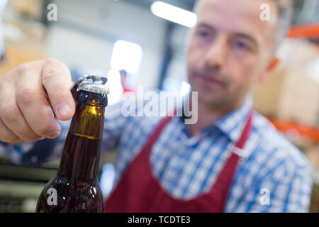 Freuen Mann das Öffnen einer Flasche Alkohol in der Brauerei Stockfoto