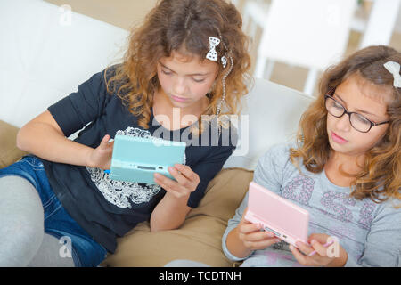 Zwei junge Mädchen, Handheld Spiele Konsolen Stockfoto
