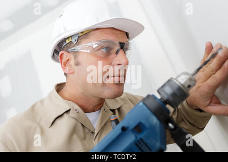 Tischler Bohrer ein Loch mit einer elektrischen Bohrmaschine Stockfoto