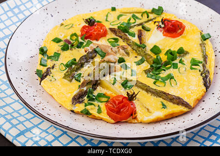 Omelett mit Spargel und Tomaten zum Frühstück auf einer hölzernen Hintergrund. Stockfoto
