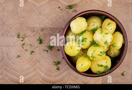 Gekocht gekochte Kartoffeln mit Dill in Schüssel auf Holzbrett. Ansicht von oben Stockfoto