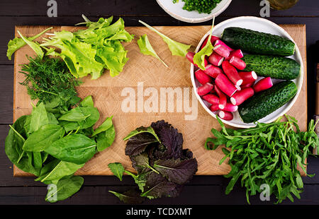 Zutaten für frischen Salat aus Gurken, Radieschen und Kräutern. Flach. Ansicht von oben