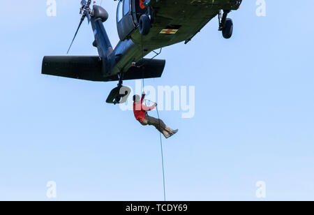 Eine Alaska Army National Guard UH-60 Black Hawk der 1 Bataillon, 207 Aviation Regiment schwebt über einem Feld zu Drop off zwei Alaska Air National Guard pararescuemen der 212th Rescue Squadron und eine Fackel für Nationale in diesem Jahr Veteranen Golden Age Spiele am Moose Run Golf Course, Joint Base Elmendorf-Richardson, 5. Juni 2019. Die nationalen Veteranen Golden Age Spiele ist eine Rehabilitation Programm in den Vereinigten Staaten entworfen, um die Lebensqualität für ältere Veteranen durch Förderung der Einbeziehung der körperliche und sportliche Aktivitäten zu verbessern. (U.S. Army National Guard Foto von Pvt. Gnade Necha Stockfoto