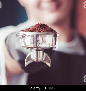 Junge barista Mann mit Filterhalter mit geerdetem Kaffee. Close Up. Quadratisches Bild. Stockfoto