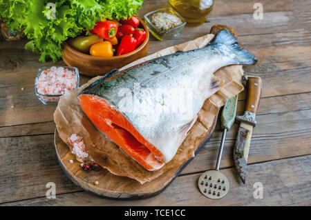 Leckere Lachsfilet, reich an Omega-3-Öl, aromatische Gewürze Gemüse und Zitrone auf frische Salatblätter auf Holz- Hintergrund. Gesundes Essen, Keto di Stockfoto