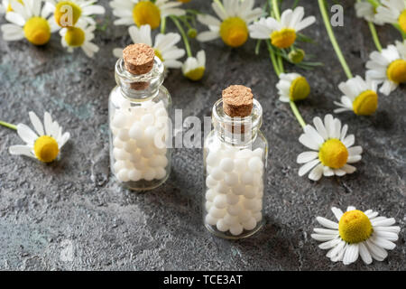 Flaschen von homöopathischen Mitteln mit frischen Kamillenblüten Stockfoto