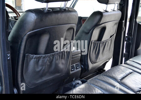 Close-up auf der Vorderseite alte Klassiker Rückenlehne Sitz mit schwarzem Leder und Taschen, der verwendeten Fahrzeug in schlechtem Zustand im Inneren nach einze Stockfoto