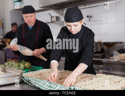 Professionelle female Koch in Vorbereitung der Eiszapfen Brötchen aus frischen Nudeln Blätter eingelegt und Hackfleisch Stockfoto