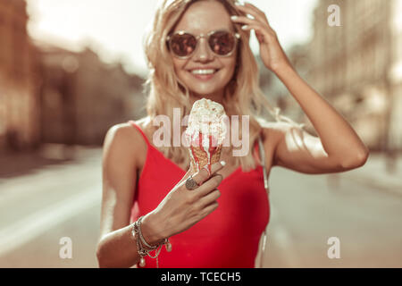 Frau mit einem Eis. Gesicht - Portrait von ansprechenden verführerisch gut - charmante suchen Blonde langhaarige Junge-erwachsene Frau das Tragen der roten Kleid halten Eis Stockfoto