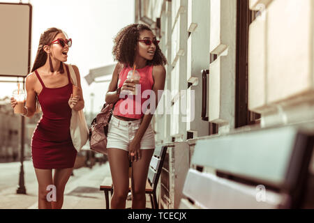 Flanieren durch die Straßen. Stilvolle Dunkelhaarige erstaunt attraktive Damen zu Fuß durch die Straßen und schauen sich die Windows gegerbt Stockfoto