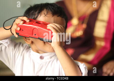 Maski, Indien, 24. Mai 2019: Kleine Indische kid versuchen, das Foto mit der Kamera zu Hause zu erfassen. Stockfoto