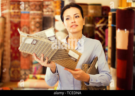 Lächelnd weibliche demonstrieren, Varianten der Teppiche home Einrichtungshaus Stockfoto