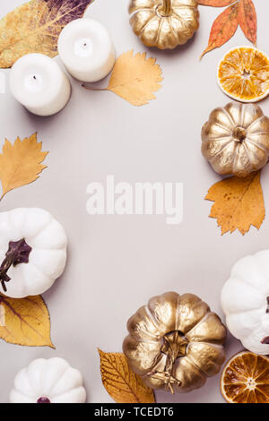 Goldenen Kürbis, trockene Blätter und Kerze Frame auf grauem Hintergrund. Herbst - Konzept. Stockfoto