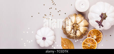 Dekorative Kürbisse, golden Konfetti und trockene Blätter auf grauem Hintergrund. Herbst Konzept. Stockfoto