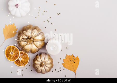 Herbst Feier Konzept. Dekorative Kürbisse, golden Konfetti und trockene Blätter auf grauem Hintergrund. Stockfoto